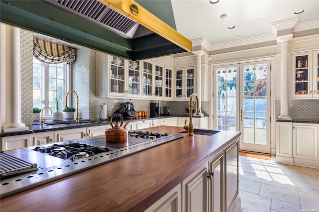 kitchen featuring gas cooktop, tasteful backsplash, ornate columns, crown molding, and sink