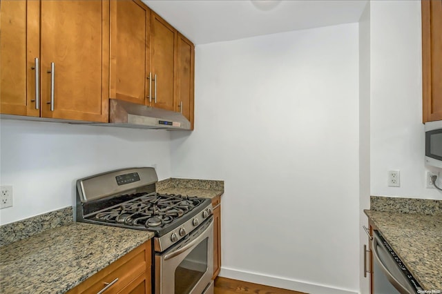 kitchen with stone countertops, wood-type flooring, and stainless steel appliances