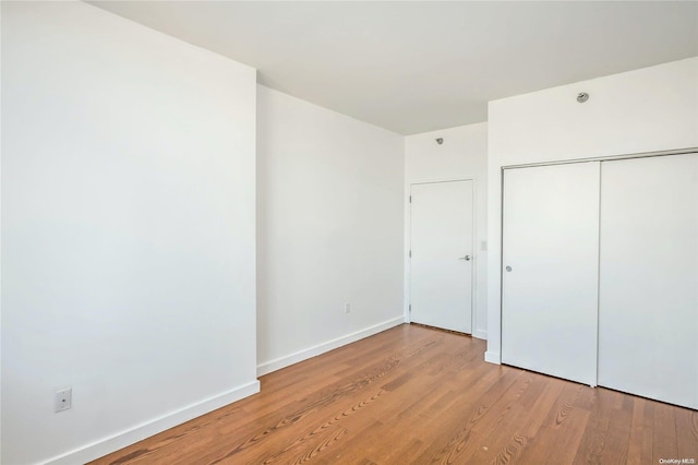 unfurnished bedroom with light hardwood / wood-style flooring and a closet