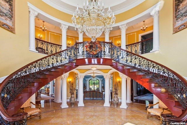 interior space with a towering ceiling, crown molding, and decorative columns