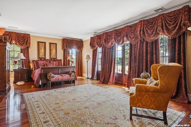 bedroom with wood-type flooring, ornamental molding, and multiple windows