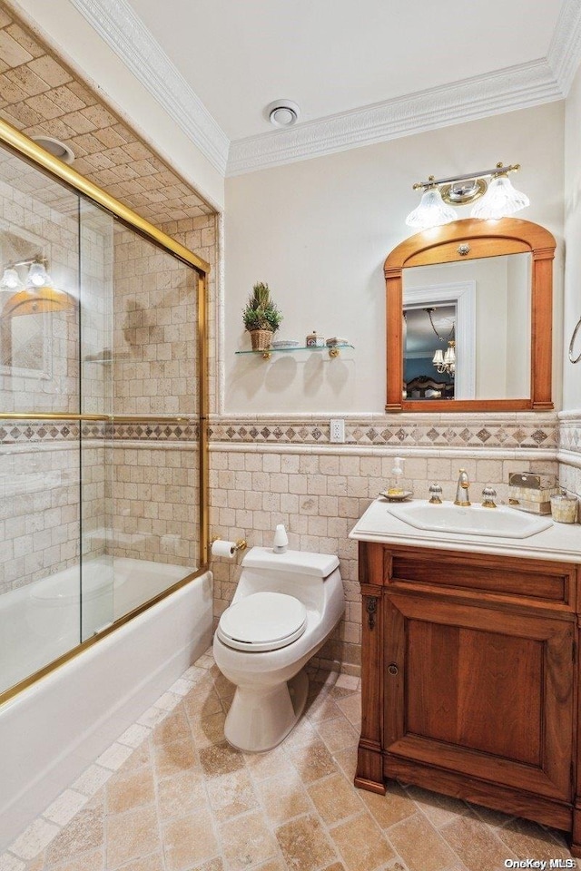 full bathroom featuring vanity, crown molding, toilet, enclosed tub / shower combo, and tile walls