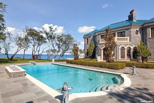 view of swimming pool with a patio area, a water view, and a diving board