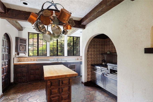 kitchen with a kitchen island, beamed ceiling, a textured ceiling, and wood counters