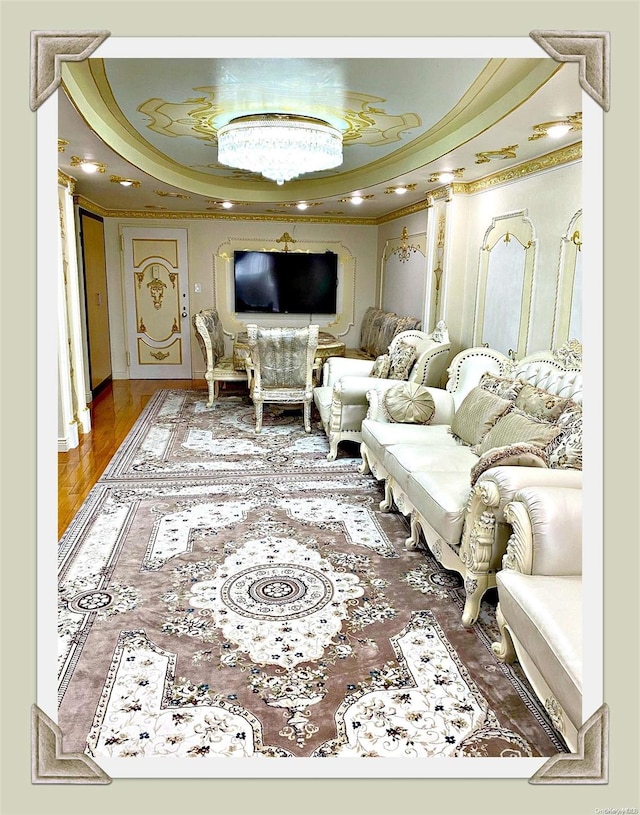 living room featuring a tray ceiling, hardwood / wood-style floors, and ornamental molding