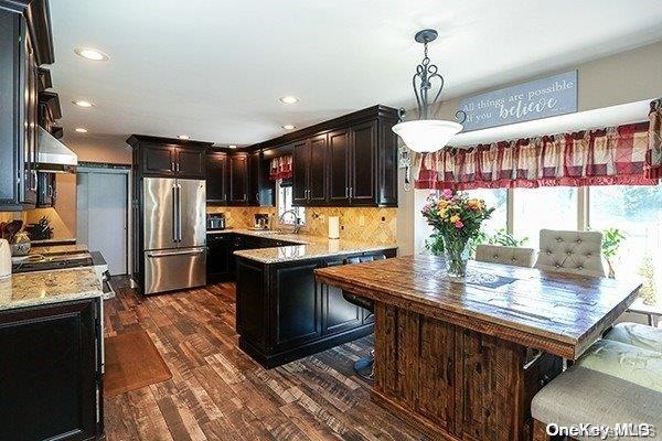 kitchen with sink, decorative light fixtures, a kitchen island, dark hardwood / wood-style flooring, and stainless steel refrigerator