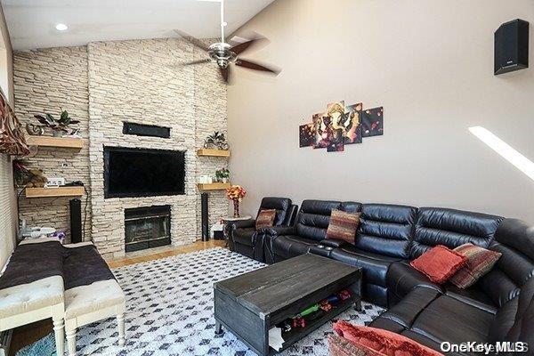 living room with a fireplace, hardwood / wood-style flooring, ceiling fan, and lofted ceiling