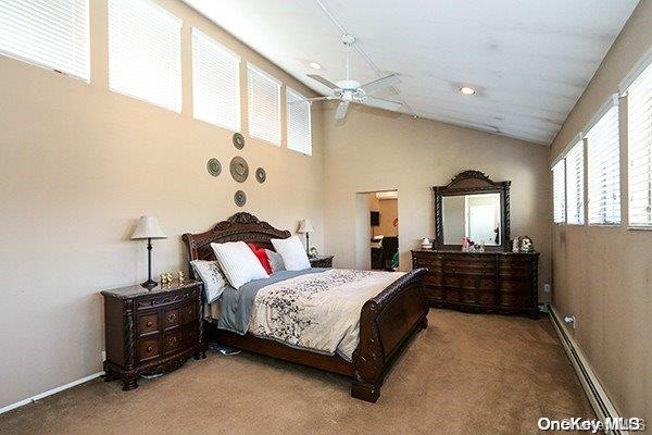 bedroom with carpet, ceiling fan, and a baseboard heating unit