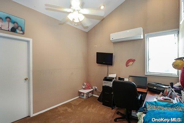 office space with a wall mounted air conditioner, carpet floors, vaulted ceiling, and ceiling fan