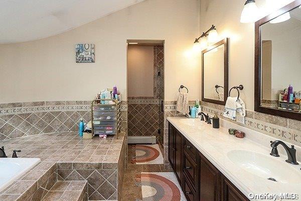 bathroom featuring vanity, tiled bath, and vaulted ceiling