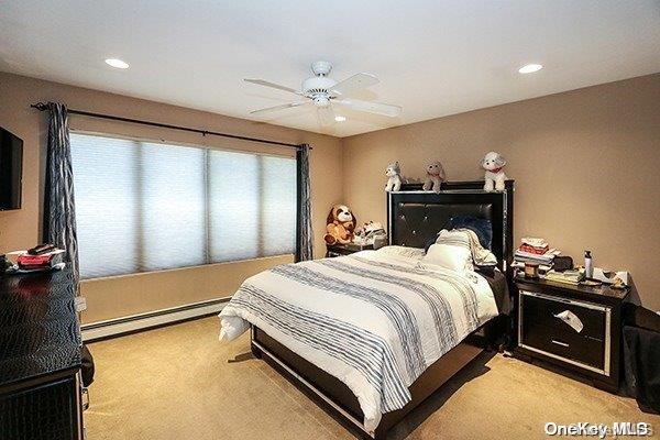 carpeted bedroom featuring ceiling fan and a baseboard heating unit