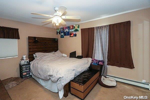 carpeted bedroom with ceiling fan and a baseboard heating unit