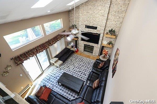 living room with a fireplace, high vaulted ceiling, and ceiling fan