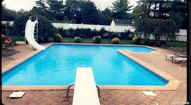 view of swimming pool with a diving board and a water slide