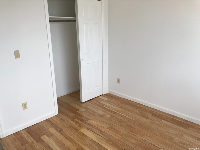 unfurnished bedroom with light wood-type flooring and a closet