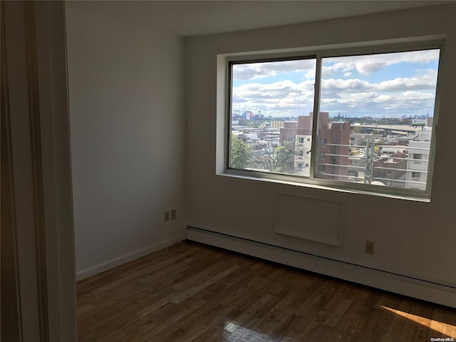 empty room with baseboard heating and dark hardwood / wood-style flooring