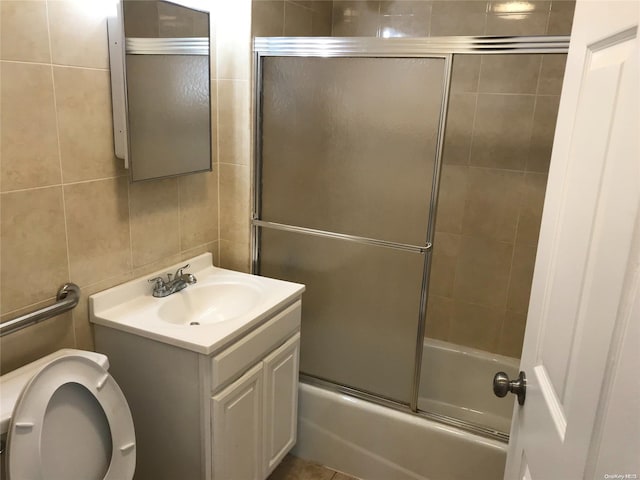 full bathroom featuring vanity, bath / shower combo with glass door, tile walls, and toilet