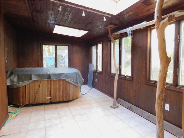 bedroom with a skylight, wooden walls, and multiple windows