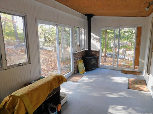 sunroom with plenty of natural light, a wood stove, and vaulted ceiling