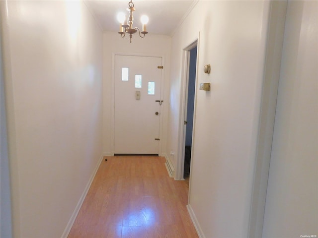 entryway featuring crown molding, light hardwood / wood-style flooring, and a notable chandelier