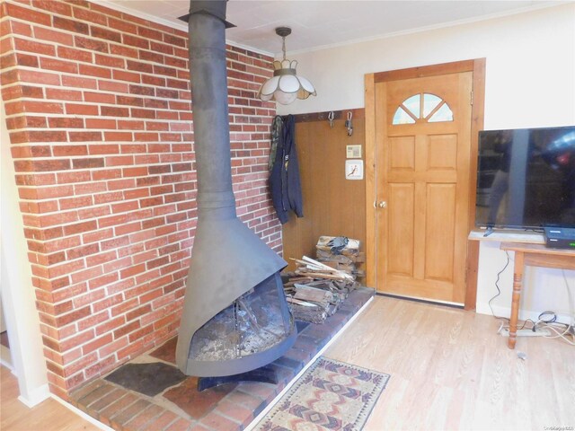 entryway featuring a wood stove, wood-type flooring, and ornamental molding