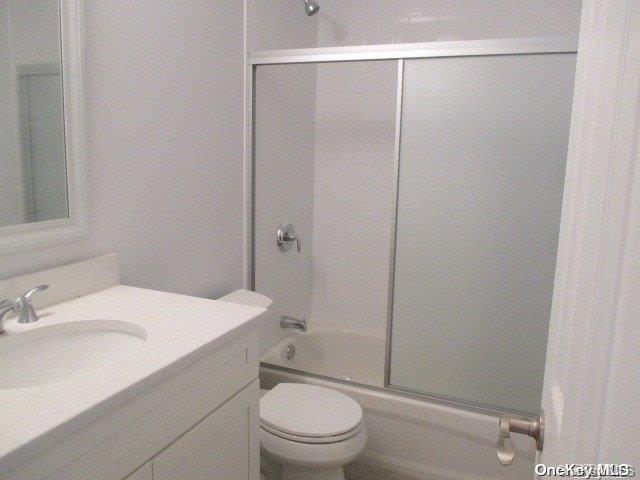 full bathroom with shower / bath combination with glass door, vanity, and toilet