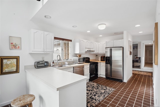 kitchen featuring white cabinetry, sink, stainless steel appliances, kitchen peninsula, and dark tile patterned flooring