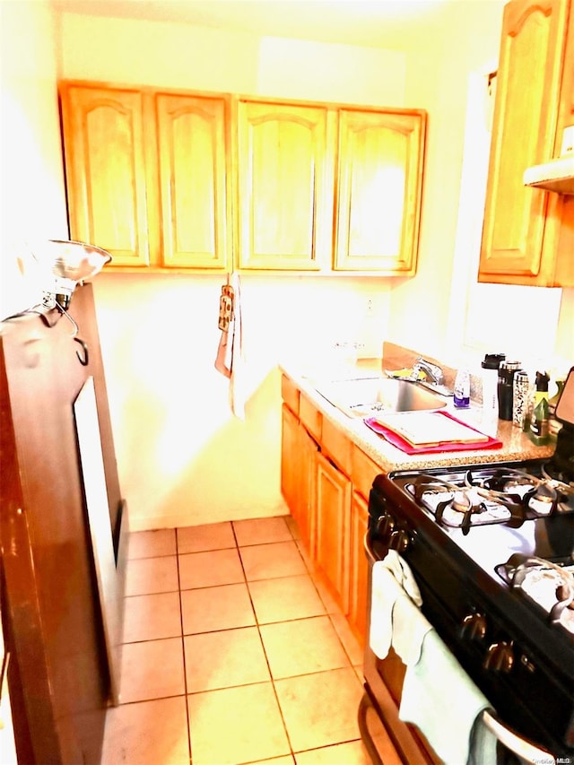 kitchen featuring light brown cabinets, white gas range, sink, and light tile patterned floors