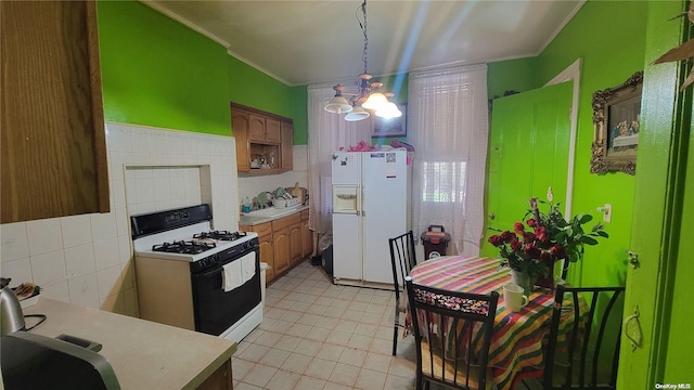 kitchen with hanging light fixtures, a notable chandelier, white appliances, tile walls, and ornamental molding