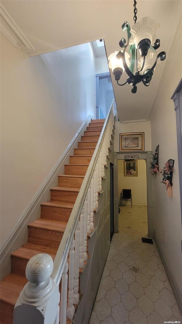 staircase featuring crown molding and an inviting chandelier