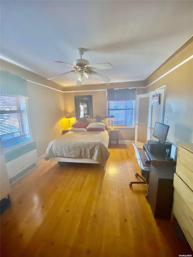 bedroom with ceiling fan, wood-type flooring, and radiator heating unit