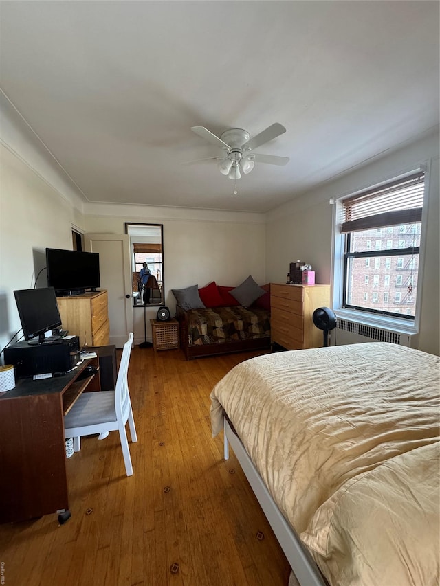 bedroom featuring crown molding, ceiling fan, wood-type flooring, and radiator