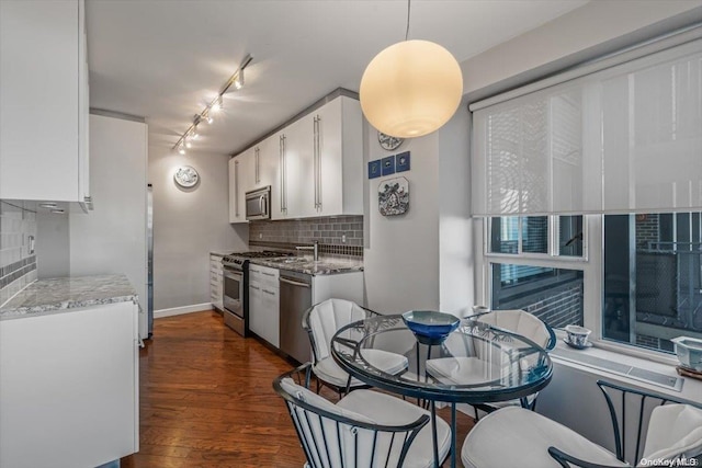 kitchen with white cabinetry, hanging light fixtures, dark hardwood / wood-style floors, decorative backsplash, and appliances with stainless steel finishes