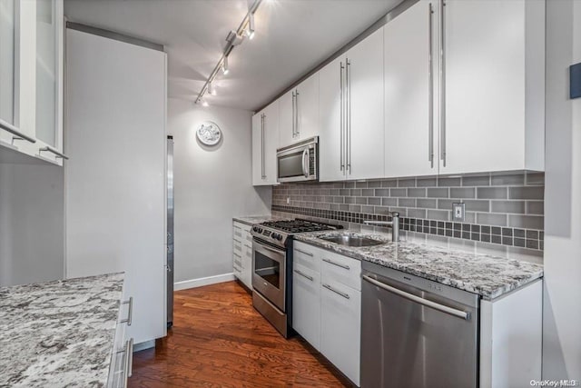 kitchen with white cabinets, sink, light stone countertops, appliances with stainless steel finishes, and dark hardwood / wood-style flooring