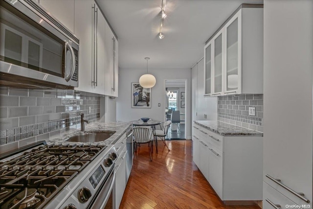 kitchen featuring white cabinetry, sink, light hardwood / wood-style flooring, decorative backsplash, and appliances with stainless steel finishes