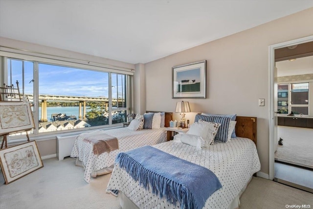 bedroom with a water view and light colored carpet