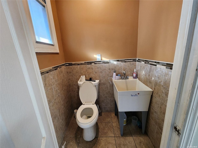 bathroom with sink, tile patterned flooring, toilet, and tile walls