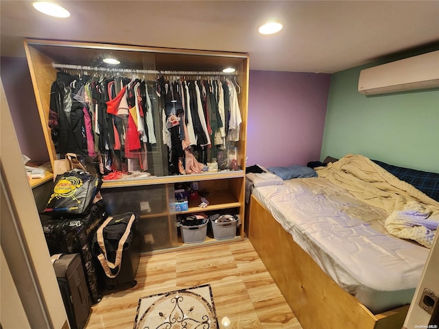 bedroom featuring wood-type flooring, a wall unit AC, and a closet