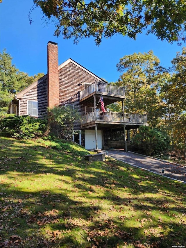 back of house with a garage, a yard, and a wooden deck