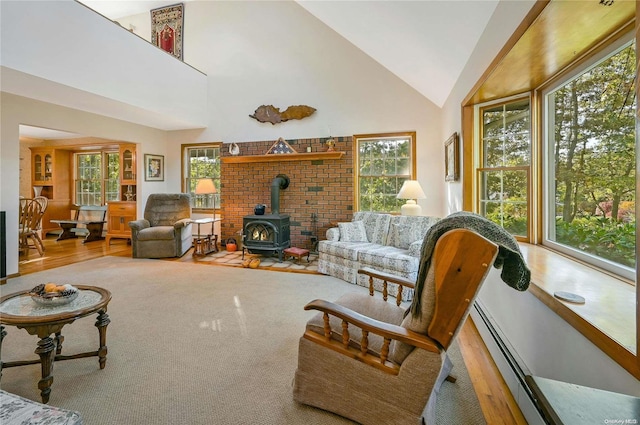 living room featuring plenty of natural light, wood-type flooring, a wood stove, and high vaulted ceiling