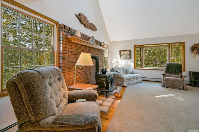 living room with wood-type flooring, a baseboard radiator, a wood stove, and a wealth of natural light