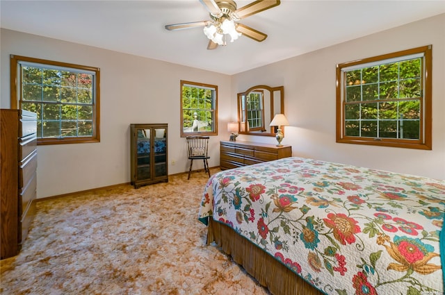 carpeted bedroom featuring multiple windows and ceiling fan