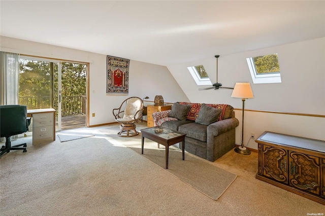 carpeted living room with ceiling fan and vaulted ceiling with skylight