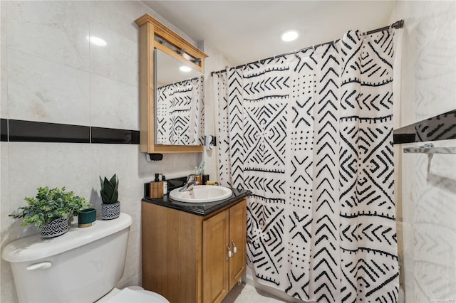 bathroom with curtained shower, vanity, tile walls, and toilet