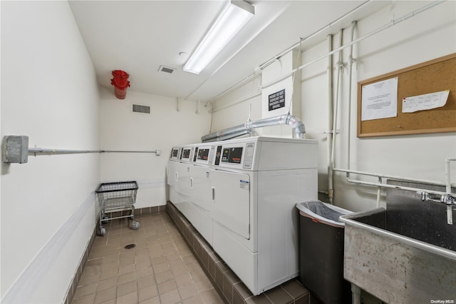 laundry area featuring light tile patterned flooring, separate washer and dryer, and sink