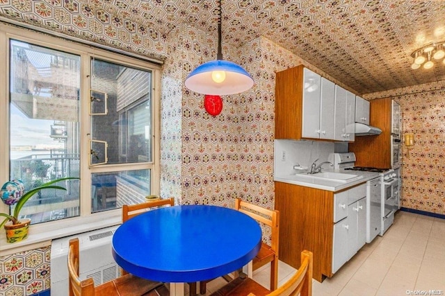 kitchen featuring backsplash, white cabinets, sink, decorative light fixtures, and white range with gas stovetop