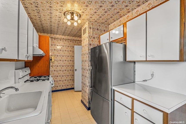 kitchen with stainless steel fridge, white cabinetry, sink, and white range with gas cooktop