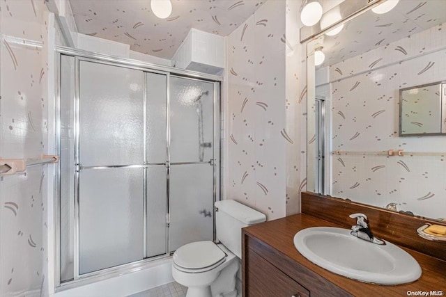 bathroom with tile patterned floors, toilet, vanity, and walk in shower