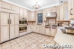 kitchen featuring cream cabinetry, a raised ceiling, exhaust hood, and an inviting chandelier