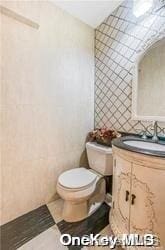 bathroom with vanity, tile walls, and toilet